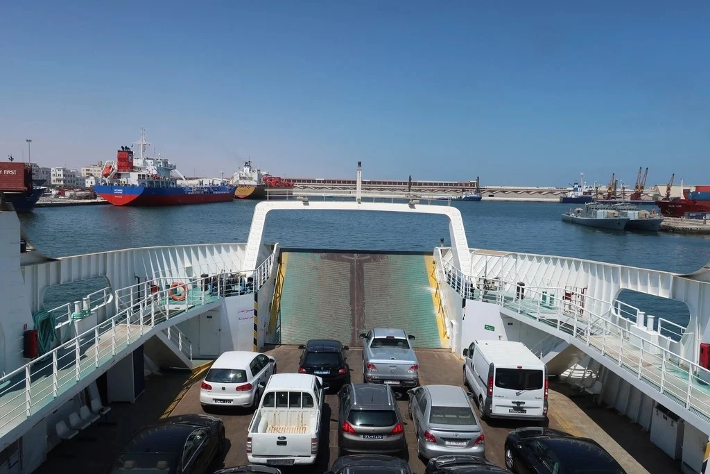 Cars parked on the open deck of a car ferry leaving port